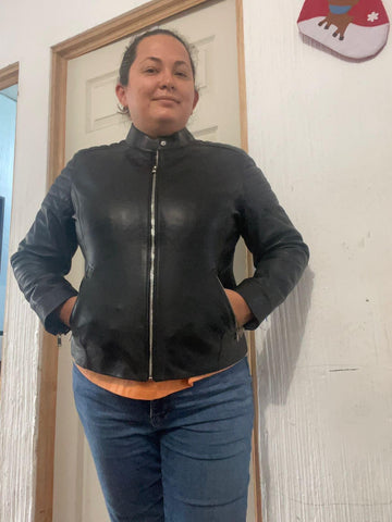 Person wearing a black leather jacket standing in front of a mirror.
